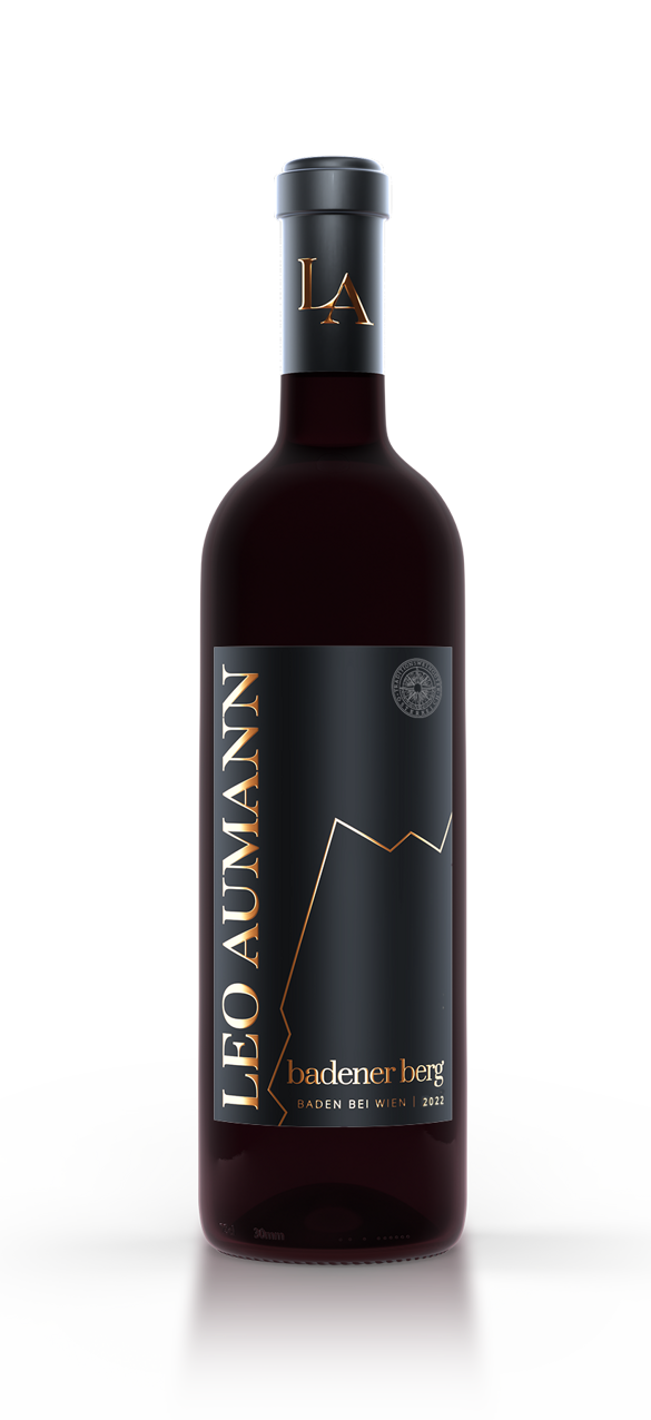 A red wine bottle by Leo Aumann with a black label and golden accents, standing on a white surface.